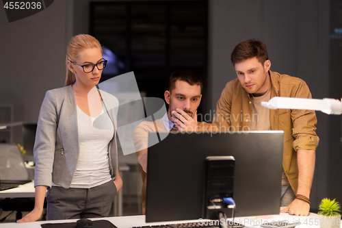 Image of business team with computer working late at office