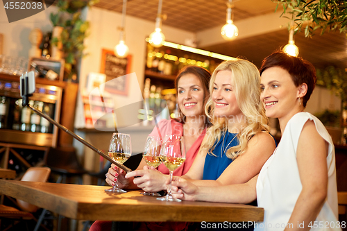 Image of women taking picture by selfie stick at wine bar