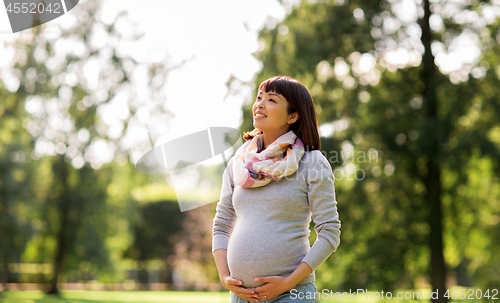 Image of happy pregnant asian woman at park