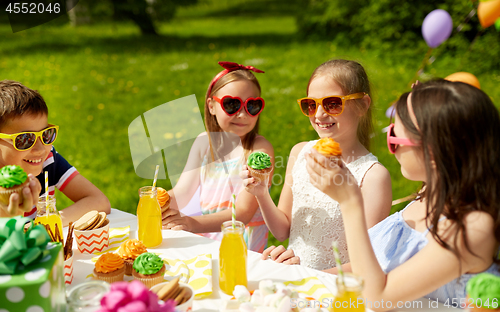 Image of kids eating cupcakes on birthday party in summer