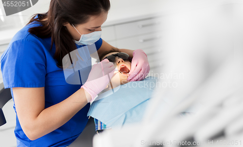 Image of dentist checking for kid teeth at dental clinic