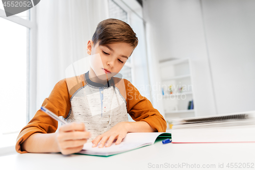 Image of boy doing homework and writing to notebook at home