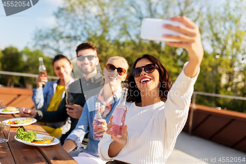 Image of happy friends taking selfie at rooftop party