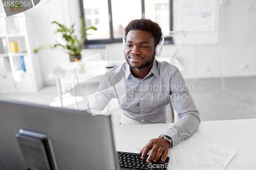 Image of businessman with headphones and computer at office