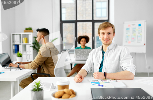 Image of male creative worker with laptop at office