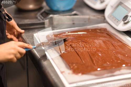 Image of confectioner makes chocolate dessert at sweet-shop