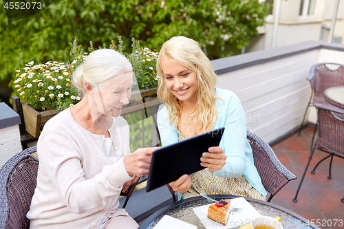 Image of daughter with tablet pc and senior mother at cafe