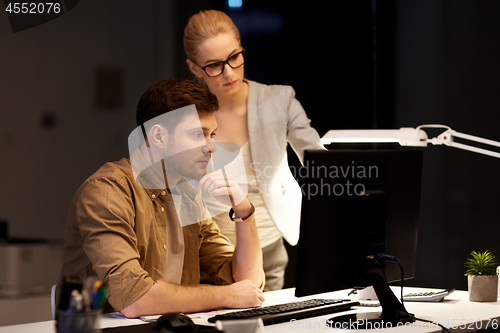 Image of business team with computer working late at office