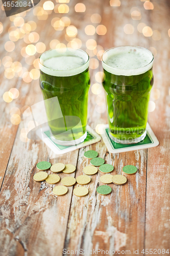 Image of glasses of green beer and gold coins on table