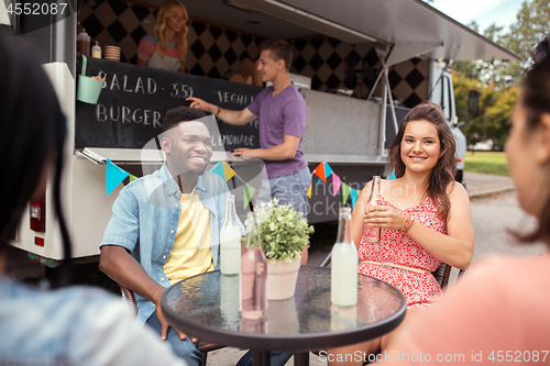 Image of friends with drinks sitting at table at food truck