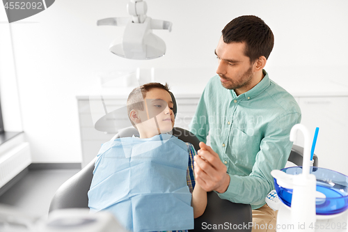 Image of father supporting son at dental clinic