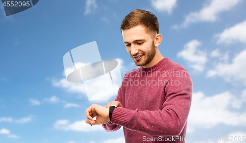 Image of smiling young man checking time on wristwatch