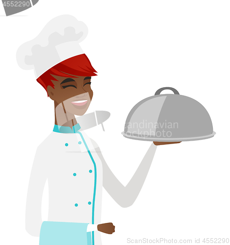 Image of Young african chef holding towel and cloche.