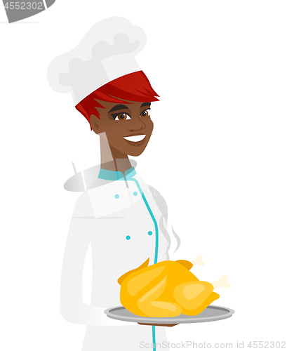 Image of Young african chef holding roasted chicken.