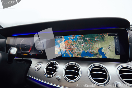 Image of View from inside a car on a part of dashboard with a navigation unit and blurred street in front of a car