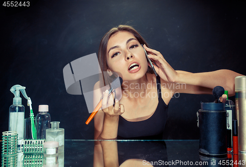 Image of Beauty woman applying makeup. Beautiful girl looking in the mirror and applying cosmetic with a big brush.