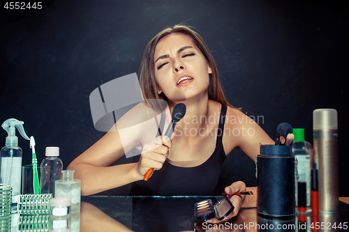 Image of Beauty woman applying makeup. Beautiful girl looking in the mirror and applying cosmetic with a big brush.