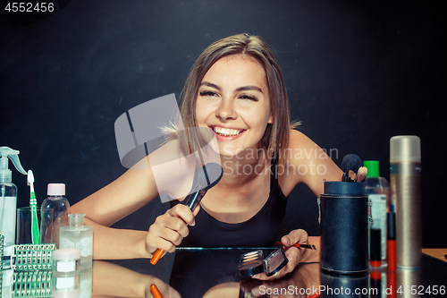 Image of Beauty woman applying makeup. Beautiful girl looking in the mirror and applying cosmetic with a big brush.