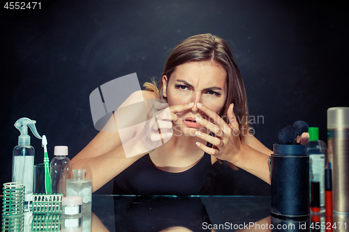 Image of Unsatisfied young woman looking at her self in mirror on black background