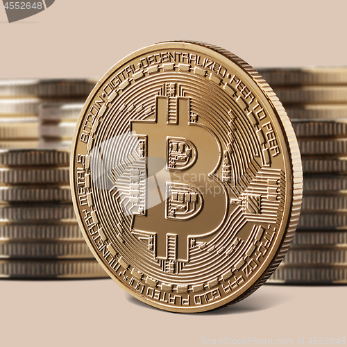 Image of Single bitcoin gold coin standing in front of stacks of coins