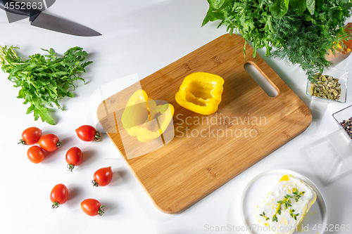 Image of A set of vegetables, tomatoes, peppers, greens and cheese for a healthy salad on a white kitchen table with copy space. Top view