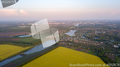 Image of Aerial view from the drone, bird\'s eye view abstract geometric forms of agricultural fields with crops, rural development of villages, lakes and rivers on a summer evening at sunset.