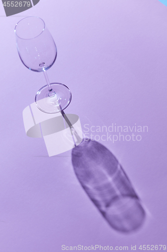 Image of wineglass sunlight and shadow on a purple background