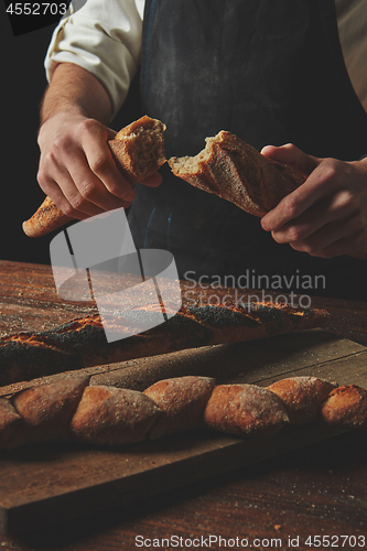 Image of Male hands break the baguette