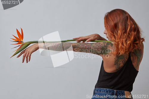 Image of Exotic strelitzia flower decorates a woman\'s hand with a tattoo 