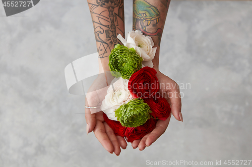 Image of girl with a tattoo on her hands holding a bouquet of flowers