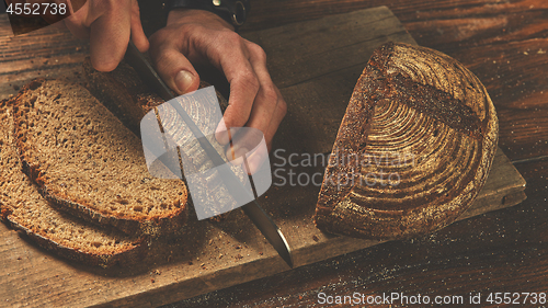 Image of Baker man slices bread