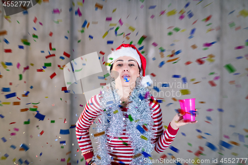 Image of business woman wearing a red hat and blowing party whistle