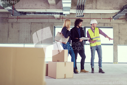 Image of architect showing house design plans to a young couple