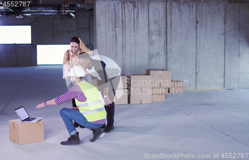 Image of engineer showing house design plans to a young multiethnic coupl