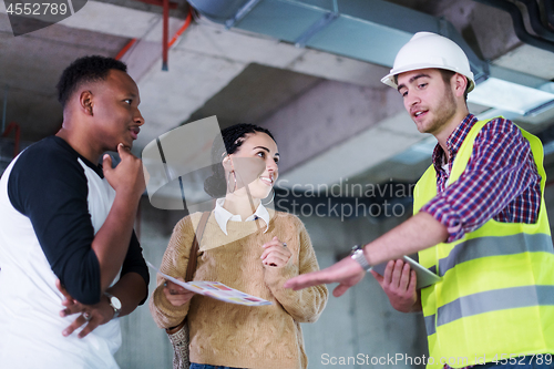 Image of architect showing house design plans to a young multiethnic coup