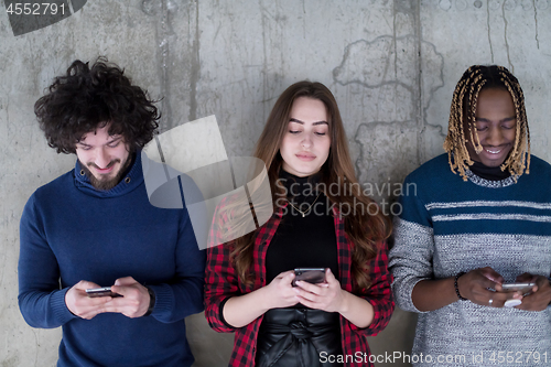 Image of casual multiethnic business team using mobile phones in front of