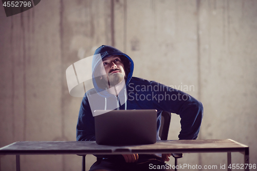 Image of talented hacker using laptop computer while working in dark offi