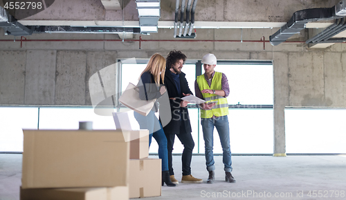 Image of architect showing house design plans to a young couple