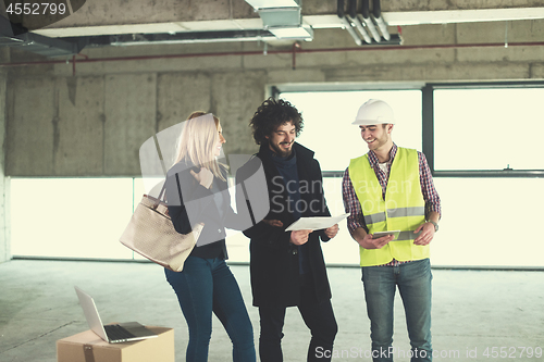 Image of architect showing house design plans to a young couple