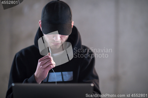 Image of talented hacker using laptop computer while working in dark offi