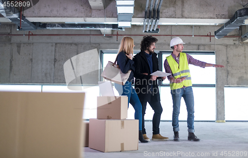 Image of architect showing house design plans to a young couple