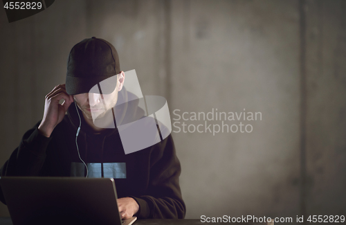 Image of talented hacker using laptop computer while working in dark offi
