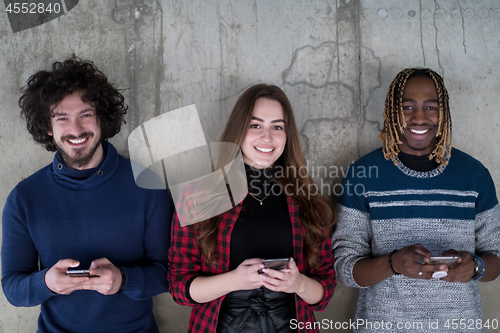 Image of casual multiethnic business team using mobile phones in front of