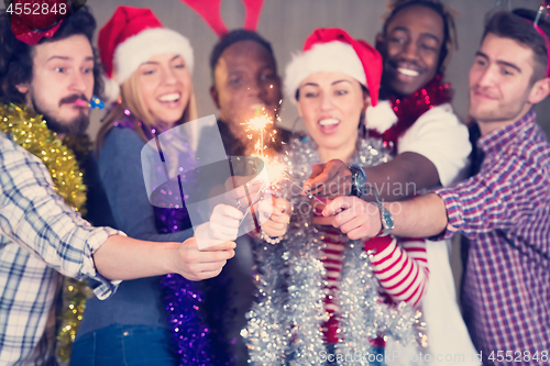 Image of multiethnic group of casual business people lighting a sparkler