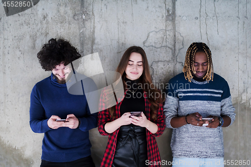 Image of casual multiethnic business team using mobile phones in front of