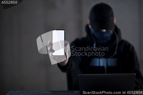 Image of criminal hacker using laptop computer while working in dark offi