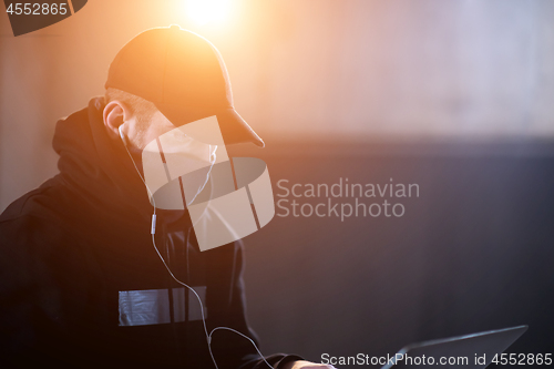 Image of young talented hacker using laptop computer while working in dar