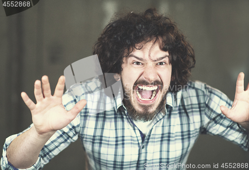 Image of casual businessman screaming in front of a concrete wall