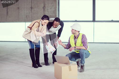 Image of engineer showing house design plans to a young multiethnic coupl