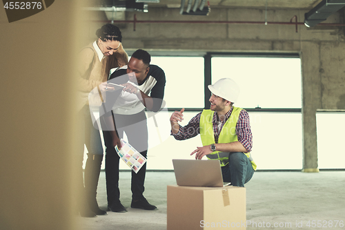 Image of engineer showing house design plans to a young multiethnic coupl